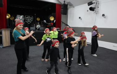 Grupa dzieci tańczy w świątecznych czapkach 